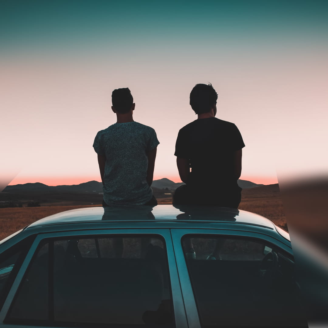 Two men sitting on top of car